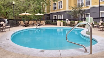 Una piscina al aire libre, sombrillas, sillones reclinables de piscina