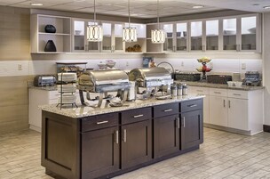 Una cocina moderna con una isla central, armarios empotrados e iluminación colgante.