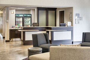 Un hall de hotel con asientos, mostrador de recepción y refrigerador para bebidas.
