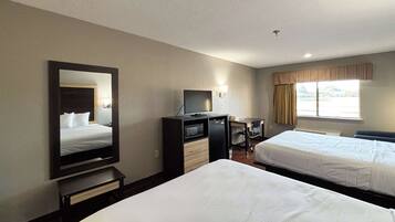 A hotel room with two beds, a desk with a computer, a TV, and a large mirror.