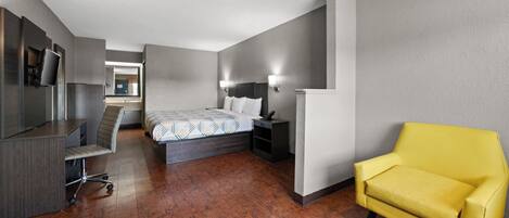 Una habitación de hotel con una cama, un escritorio, una silla, un televisor y un espejo.