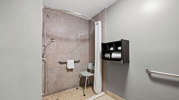 A shower area with a grab bar, a towel rack, and a shelf with towels.