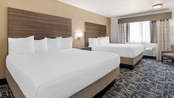 A hotel room with two beds, a chair, a nightstand, and a window with curtains.