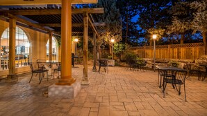 Un espace extérieur aménagé en terrasse, avec un sol en pierre, des chaises et des tables en métal.