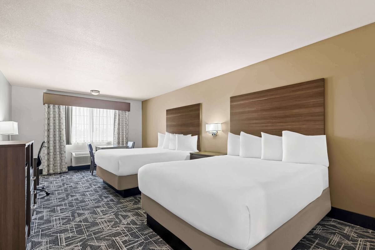 Une chambre d’hôtel avec deux lits, un bureau et une chaise.