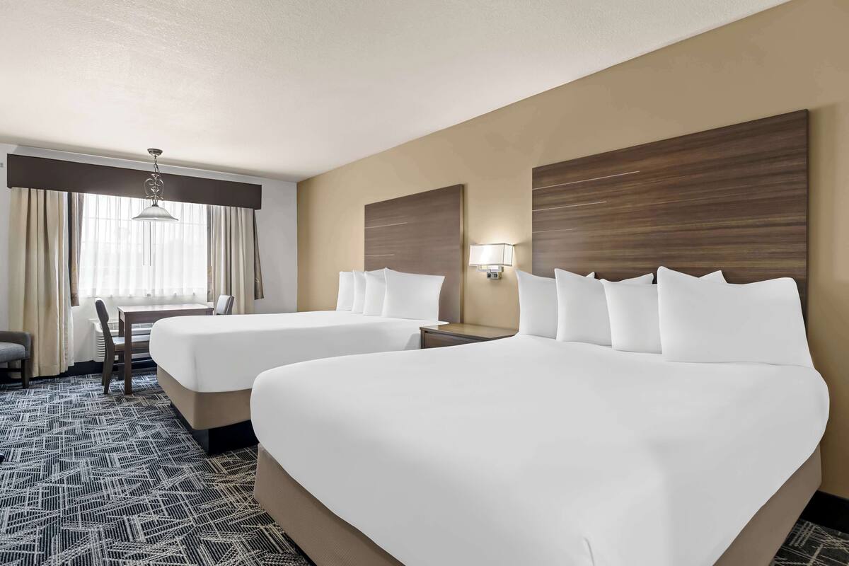 Une chambre d’hôtel avec deux lits, un bureau et une chaise.