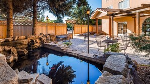 Un jardin avec un petit étang, des marches en pierre, une clôture en bois, un espace salon extérieur et une pergola.