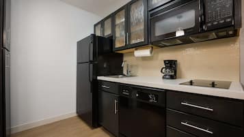 Een moderne keuken met zwarte apparaten, een wit aanrechtblad en een beige achterwand.