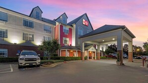 Un hotel de varios pisos con una estación de servicio adosada, que muestra un llamativo letrero 'Best Price Plus'.