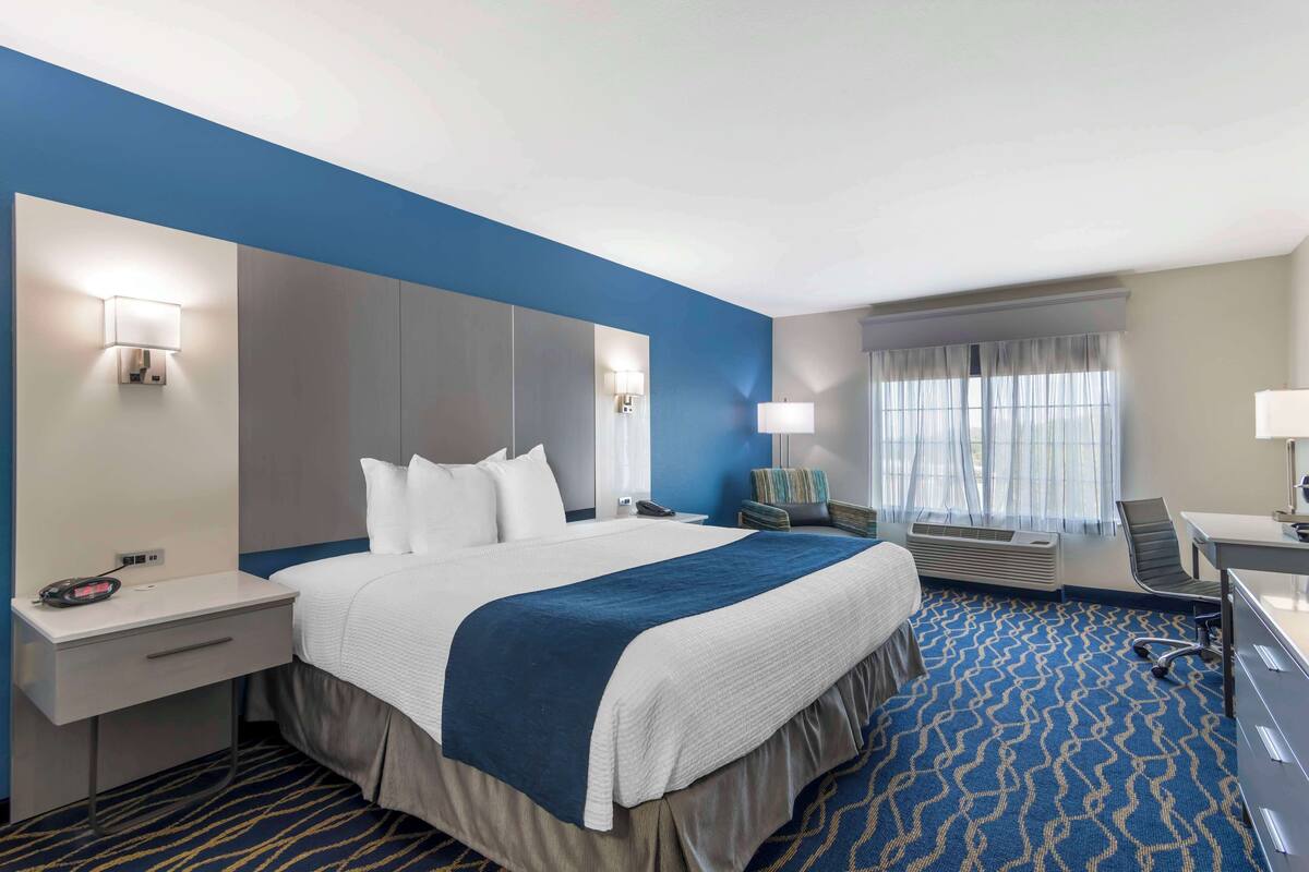 Een hotelkamer met een groot bed, een bureau, een stoel en een raam met gordijnen.