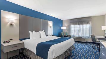Quarto de hotel com uma cama grande, uma escrivaninha, uma cadeira e uma janela com cortinas.