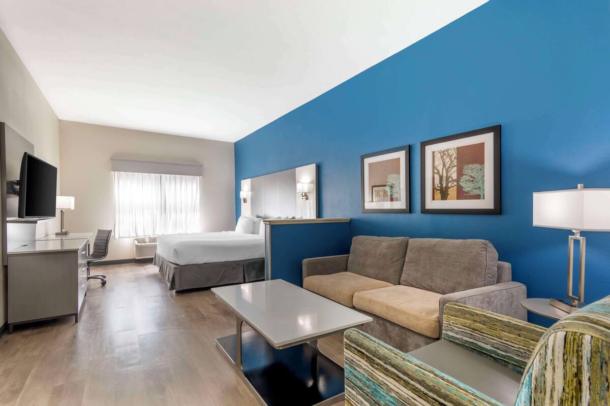 Een hotelkamer met een bed, een slaapbank, een bureau en een televisie.