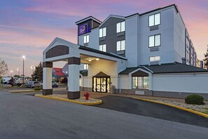 Un hôtel moderne doté d’une entrée imposante, d’un espace d’attente abrité et d’un parking.