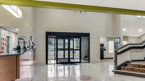 A spacious lobby with a marble floor, a reception desk, and a staircase leading to an upper level. - Sleep Inn near I-80 and I-94 (Lansing)