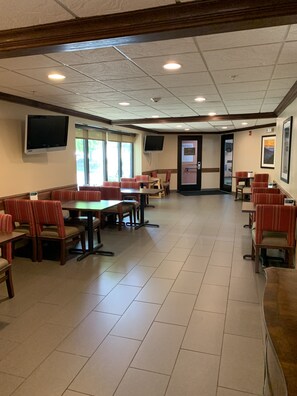 A spacious indoor dining area with multiple tables and booths, a flat-screen TV mounted on the wall, and a door labeled "Pool Rules". - Comfort Inn Franklin Highway 96 (Franklin)