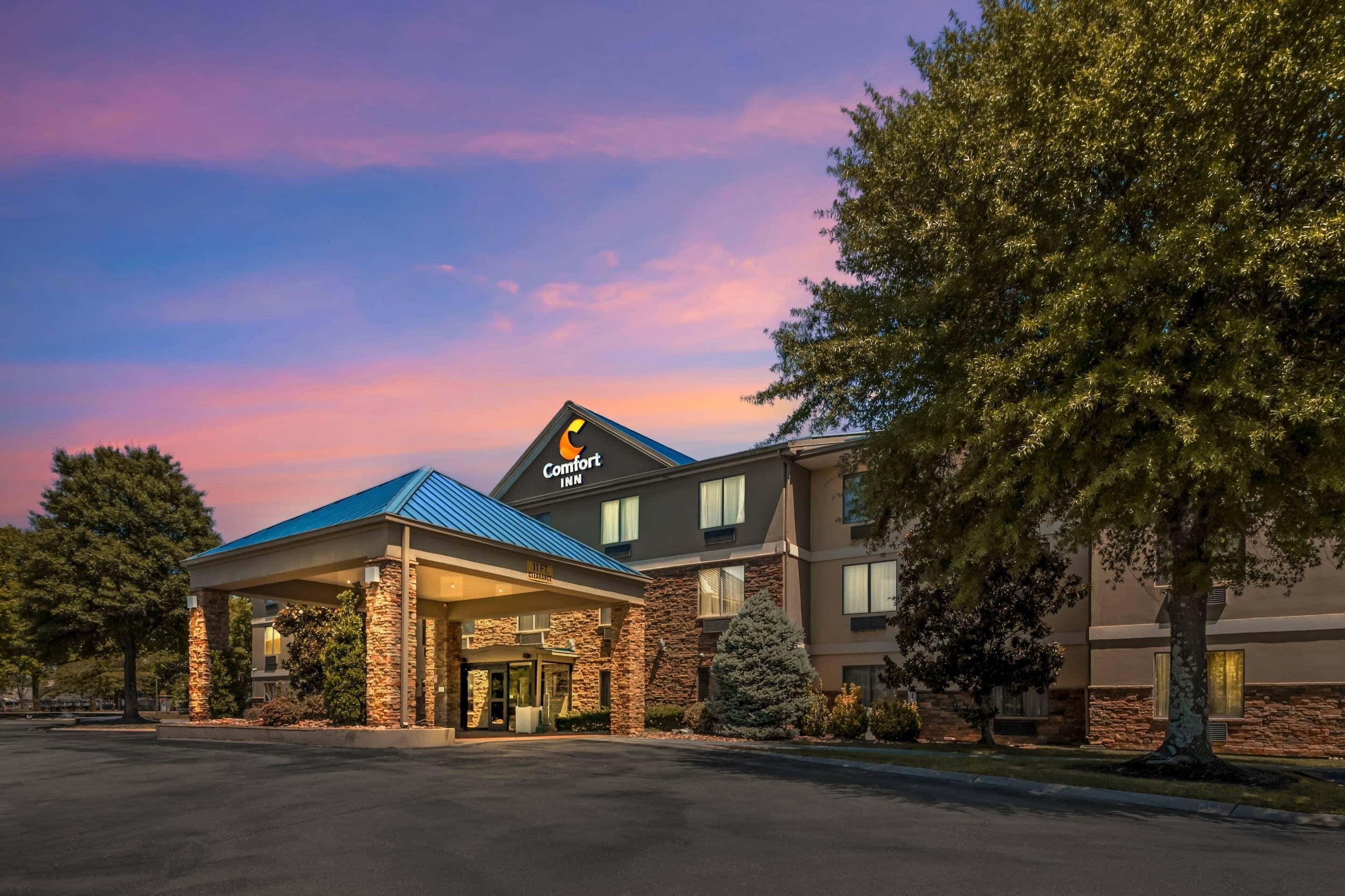 Un hotel Comfort Inn con entrada techada, fachada de piedra y estacionamiento.