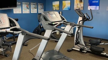 Ett gym med löpband, motionscyklar och en vägg full med motiverande affischer.