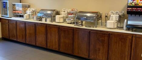 A buffet area with a refrigerated display case, multiple serving stations, and a fruit juice dispenser.