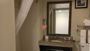 Ein Badezimmer mit einer Badewanne, einem Waschbecken mit Spiegel, einer Toilette und einer Duschvorhang.