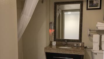 A bathroom with a bathtub, a sink with a mirror, a toilet, and a shower curtain.
