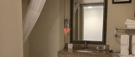 Un baño con bañera, lavabo con espejo, inodoro y cortina de ducha.