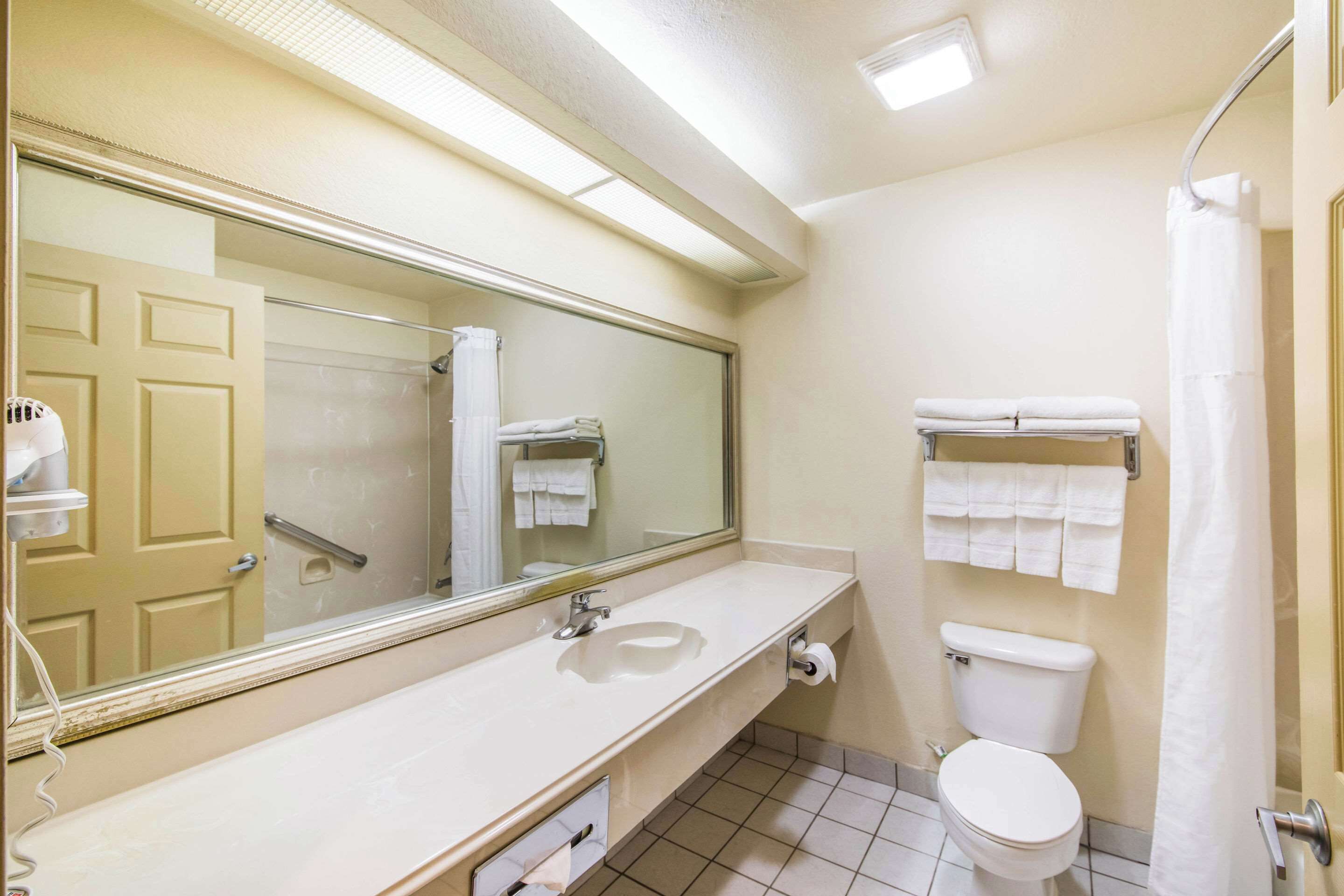 Une salle de bain équipée d’un lavabo, d’un miroir, de toilettes et d’un porte-serviettes.