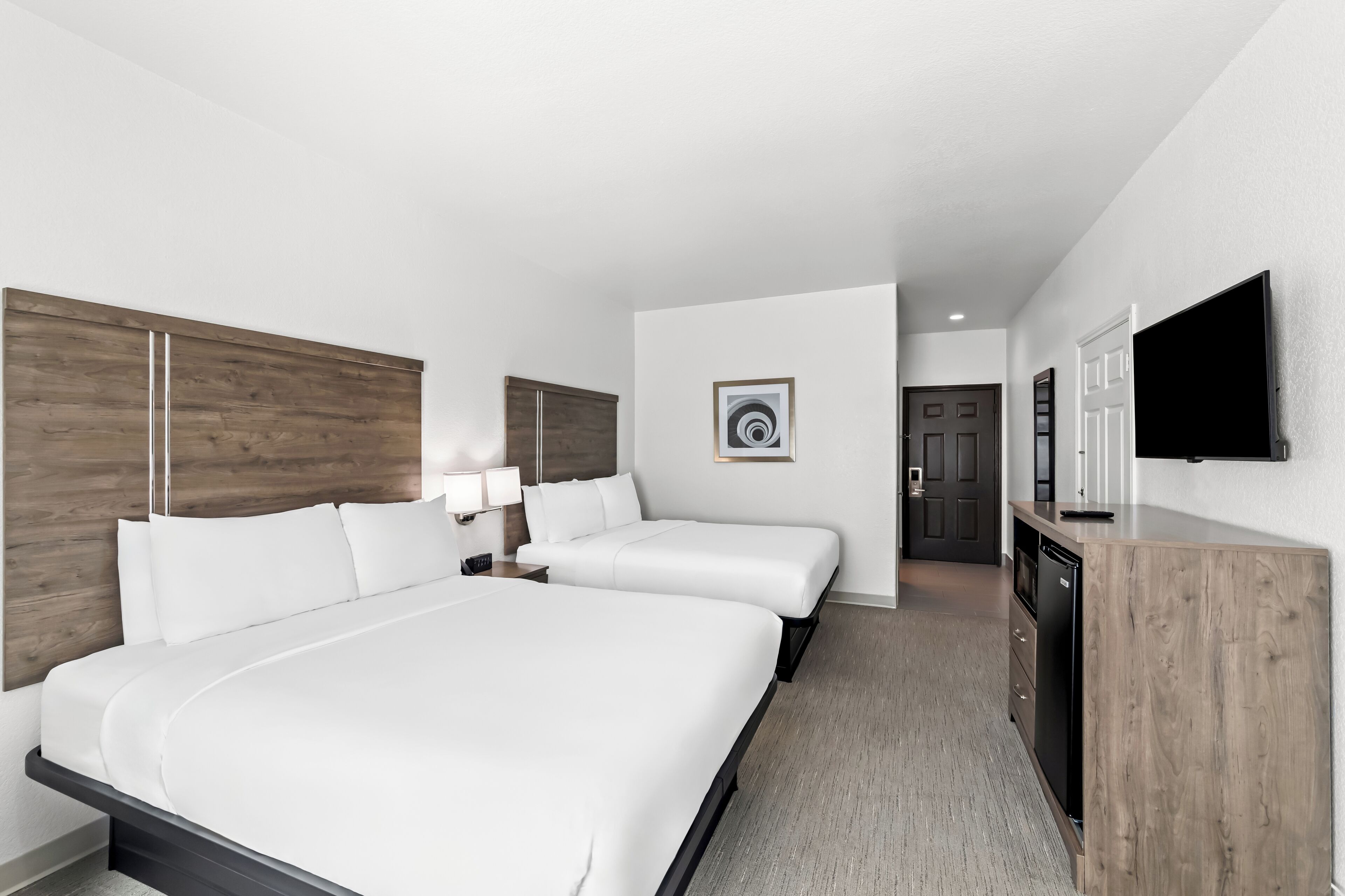A hotel room with a large bed, two bedside tables, a TV, and a wooden cabinet.