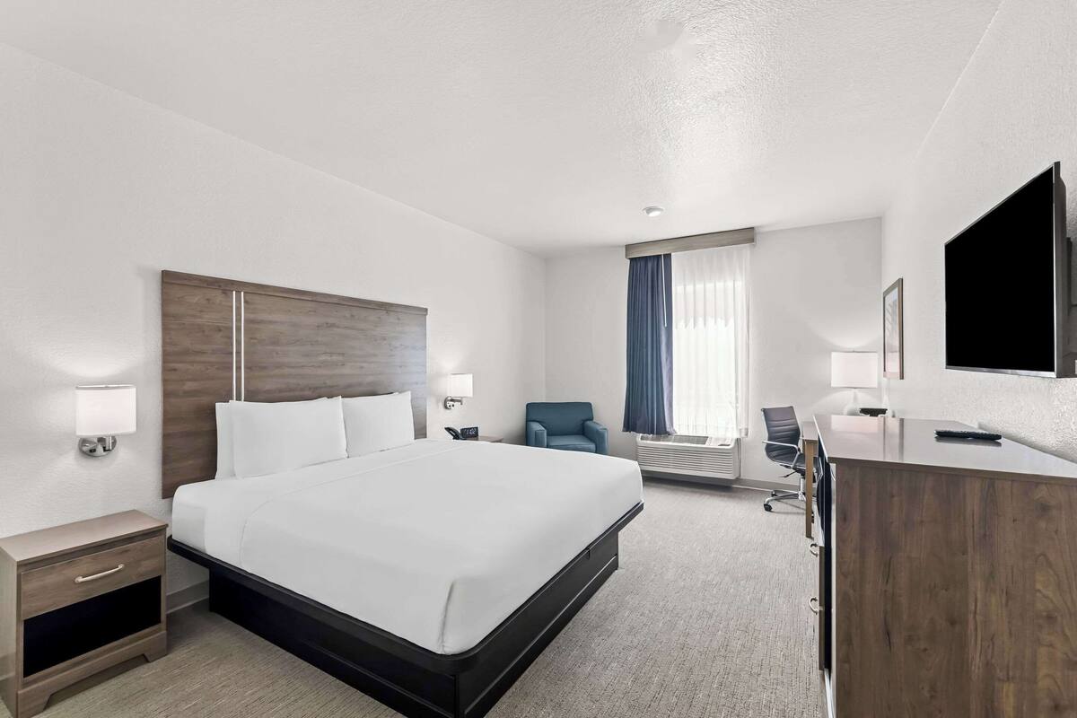 A hotel room with a large bed, a desk, a chair, and a TV.