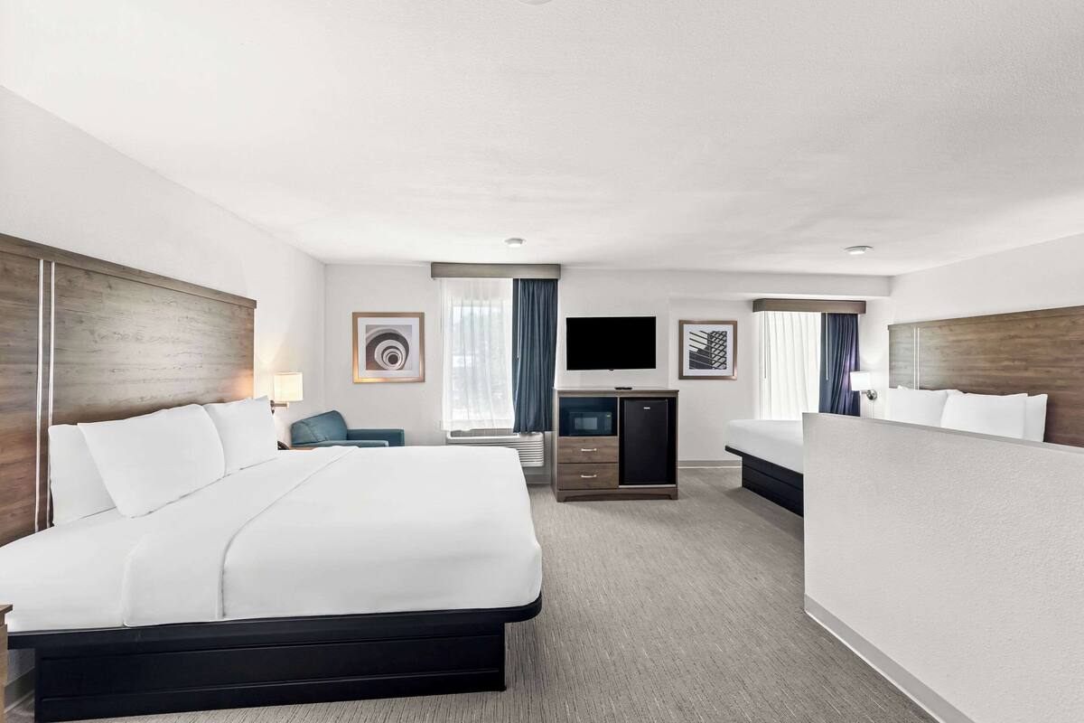 A hotel room with a large bed, a TV, a desk, and a seating area.