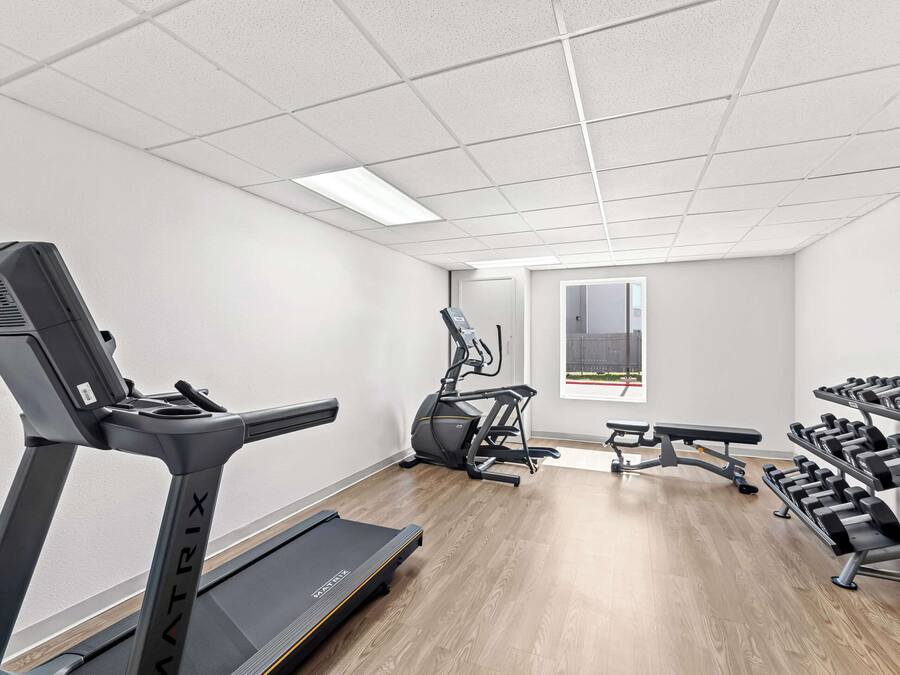 Ett gym med löpband, crosstrainer, träningsbänk och hantlar.