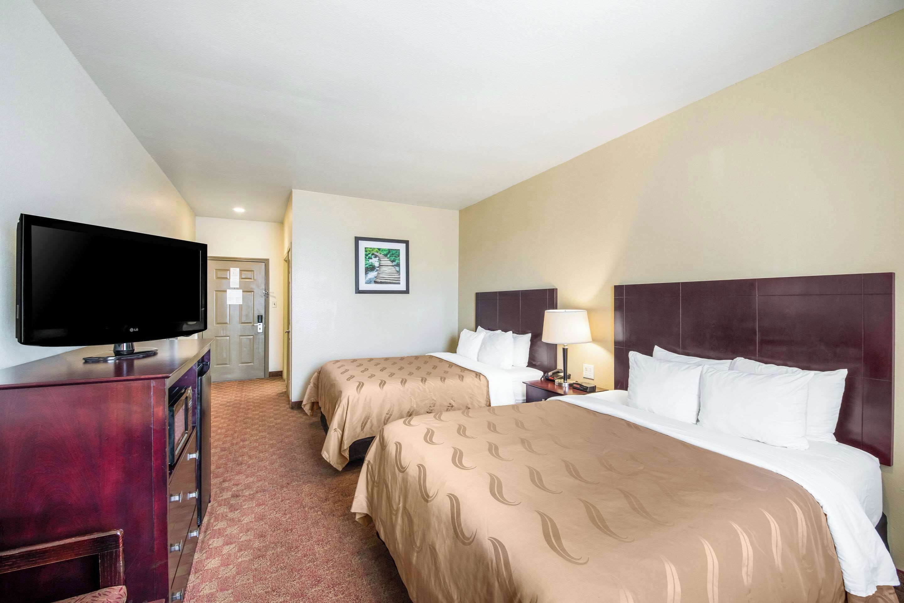 Une chambre d’hôtel avec deux lits, une télévision, un bureau et une lampe.