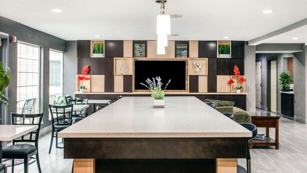 Una cocina moderna con una isla central, muebles oscuros y un ventanal grande.