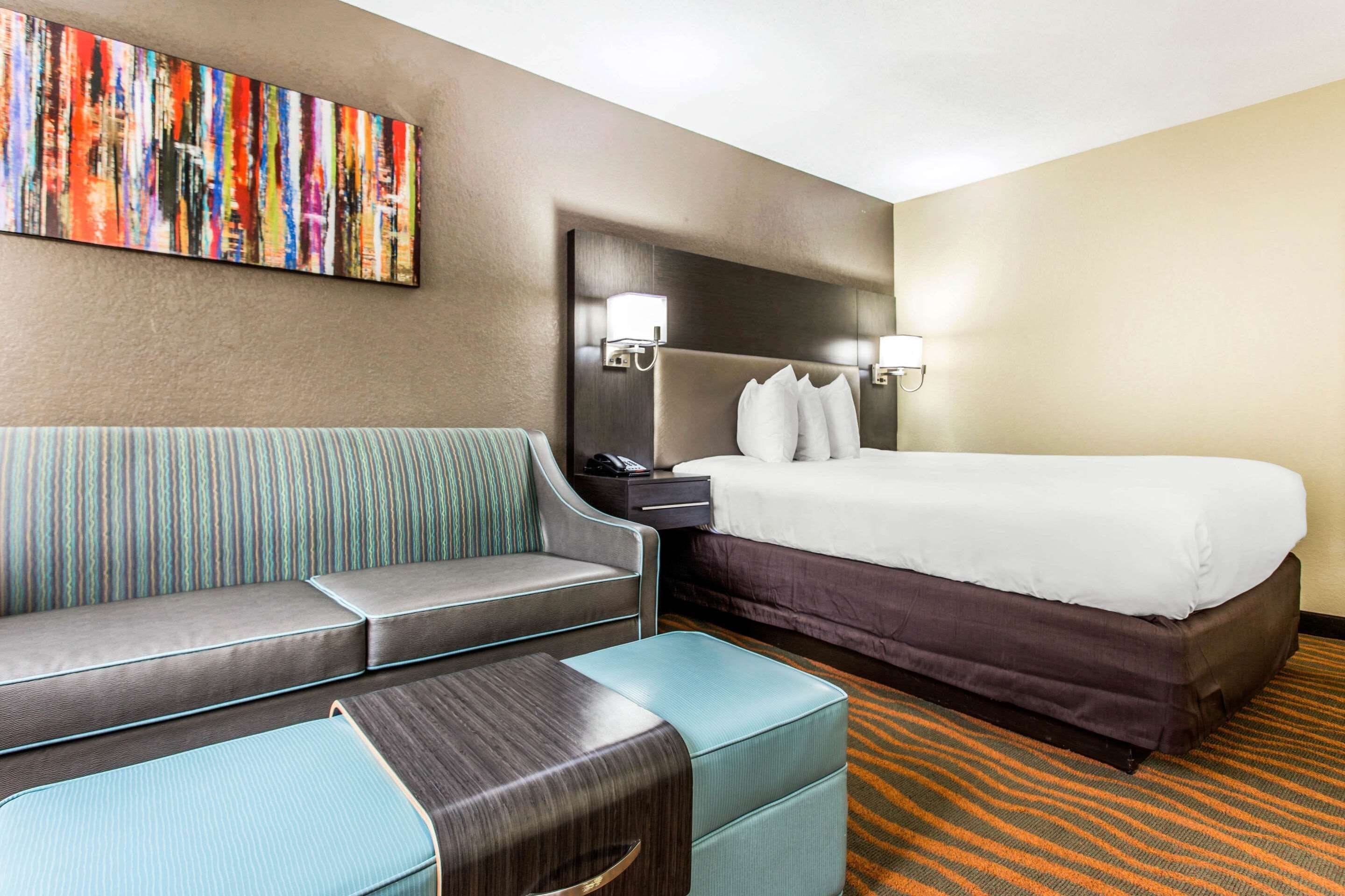 Una habitación de hotel con cama, sofá, una mesita y una mesita de noche.