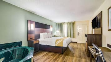 Una habitación de hotel con una cama grande, una zona de estar, una bañera y un televisor.