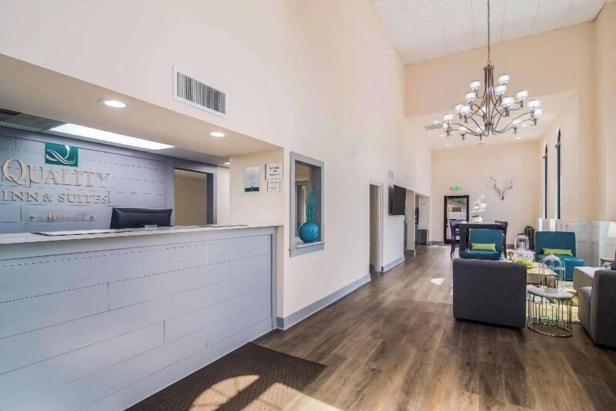 A hotel reception area with a reception desk, a chandelier, and a seating area with sofas.