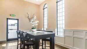 A conference room with a dark table and chairs, a vase with white flowers, and large windows with white trim. - Quality Inn & Suites Lake City (Lake City)
