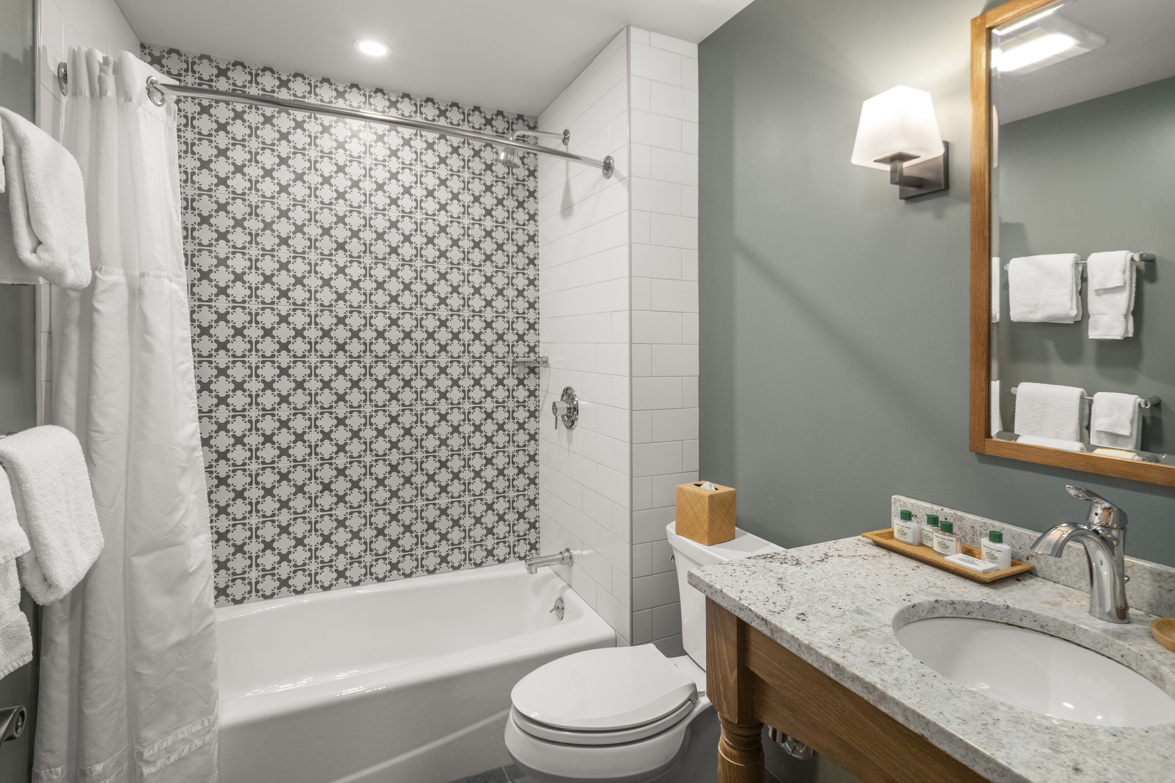 A bathroom with a bathtub, toilet, sink, and a shower curtain with a floral pattern.