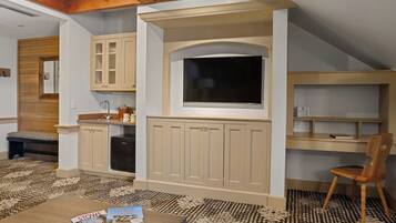 A compact kitchen with built-in cabinets, a large window, and a dining area with a table and chairs.