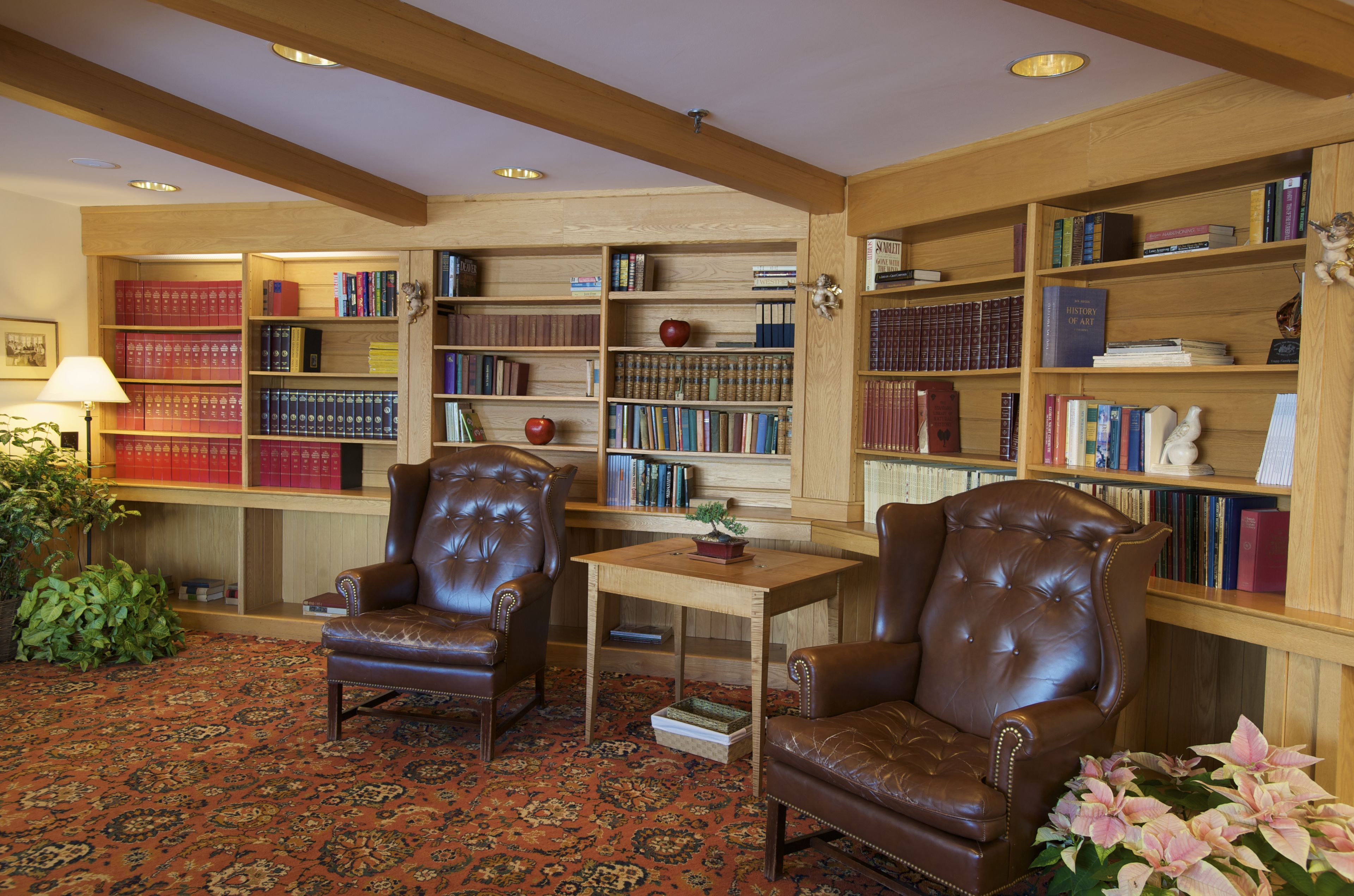 A library with leather chairs, bookshelves, and a patterned carpet.