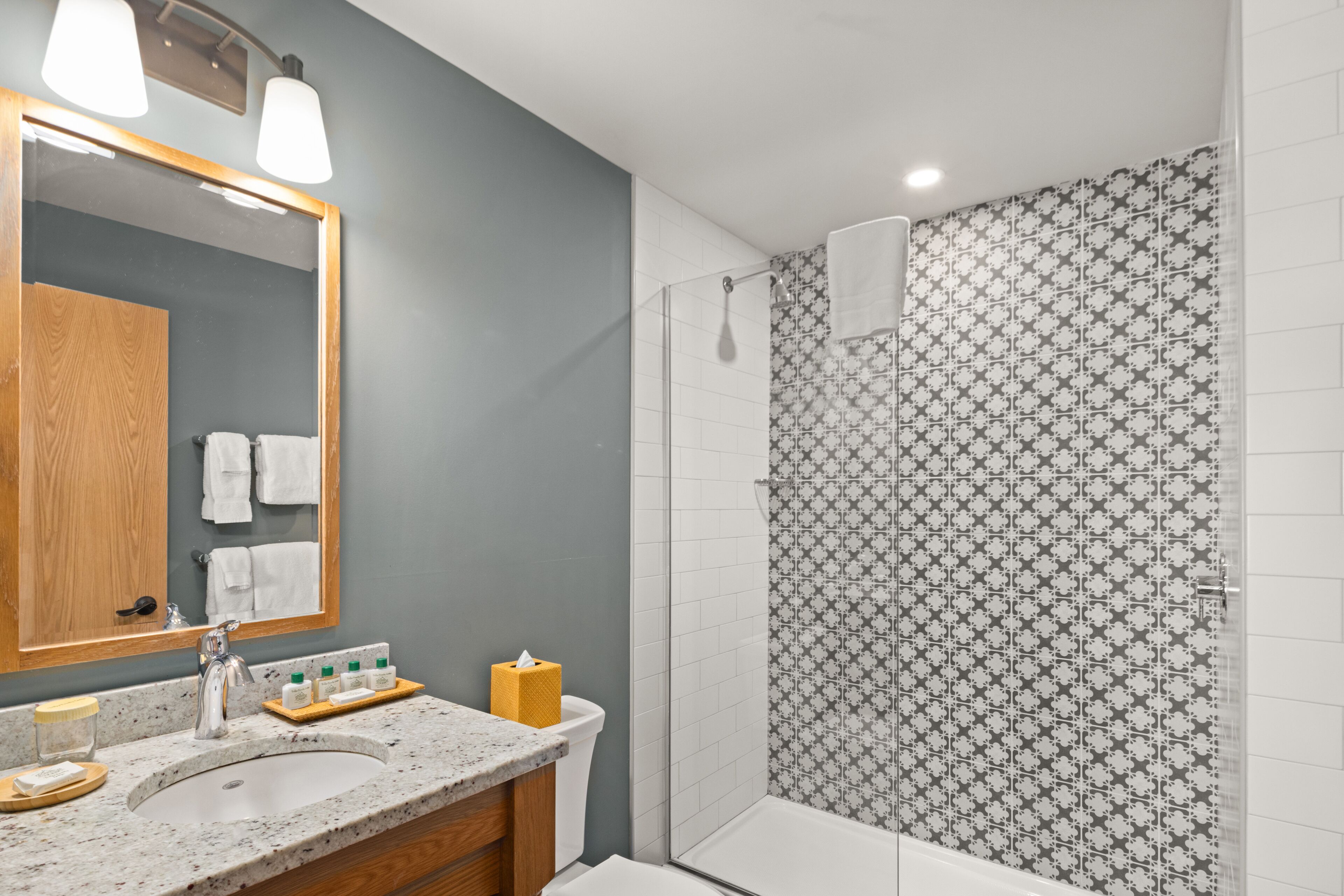 A bathroom with a sink, mirror, and shower.