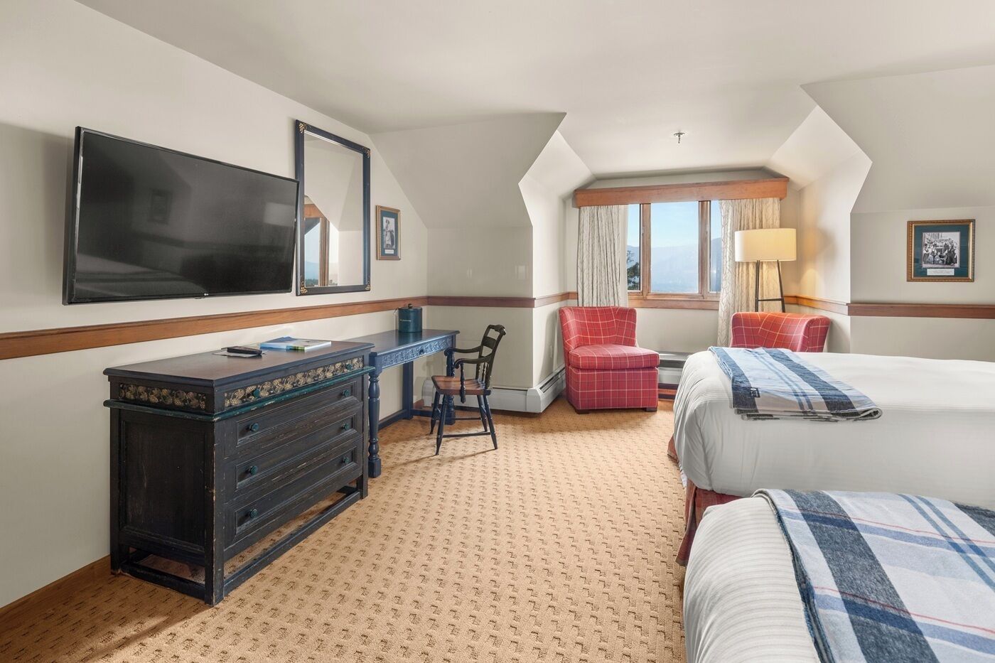 Une chambre d’hôtel avec un lit, un bureau, une chaise, une télévision et une fenêtre avec des rideaux.