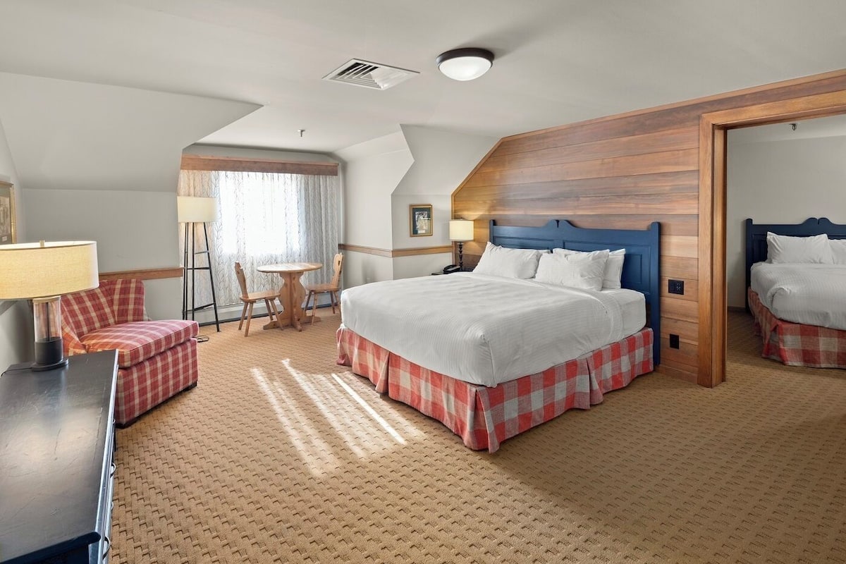 Habitación de hotel con una cama grande, un escritorio, una silla y una mesita.