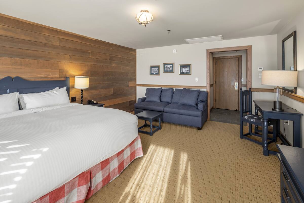 Una habitación de hotel con una cama grande, un sofá, un escritorio y un espejo.