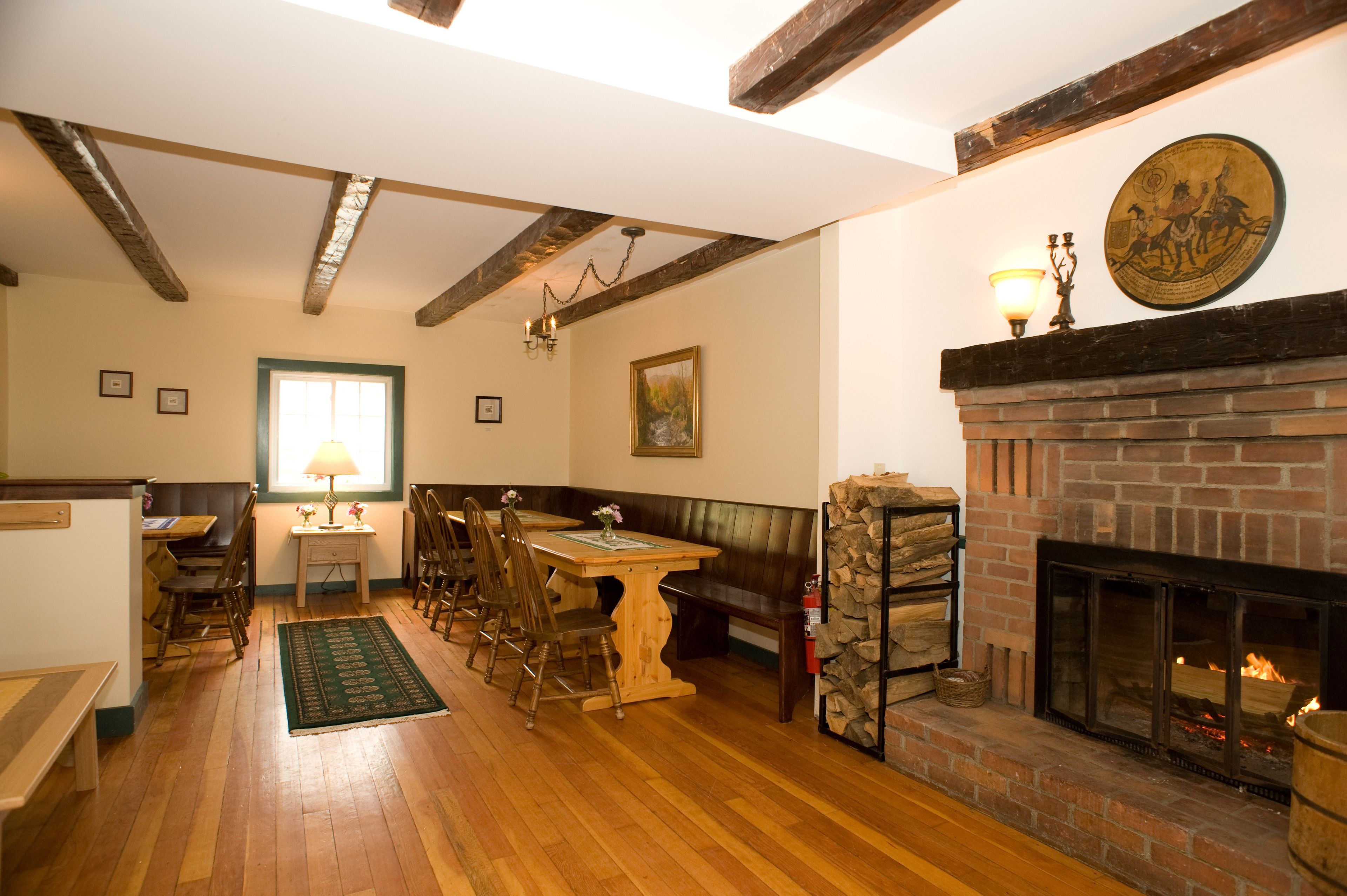 A dining area with a wooden table and chairs, a fireplace, and a stone wall.