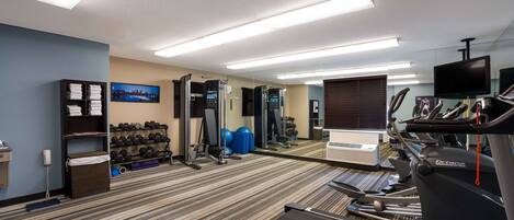 A hotel gym with treadmills, weights, and exercise balls.