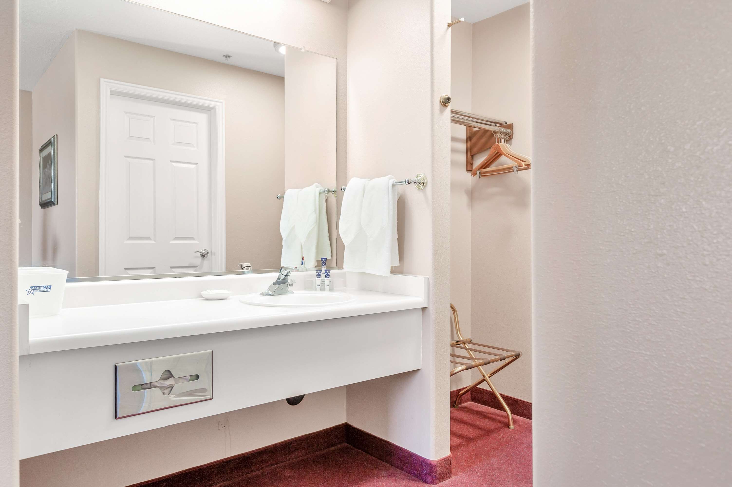 A bathroom with a white sink, a large mirror, and a towel rack.