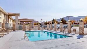 A swimming pool with lounge chairs, a covered area, and a mountain backdrop. - Americas Best Value Inn Cedar City (Cedar City)