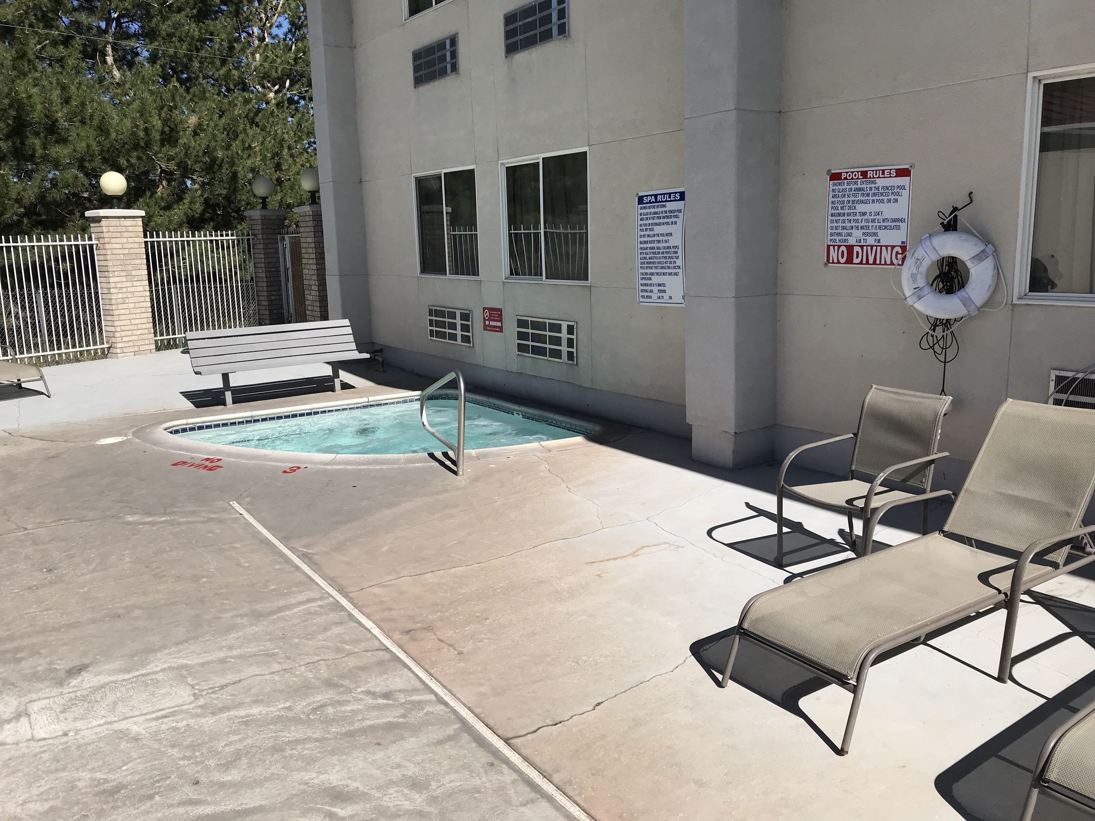 Zona de piscina con sillas de descanso, una piscina y un letrero que indica que no se permite el clavado.