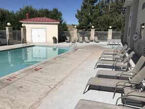 A swimming pool with lounge chairs and a small building with a red roof. - Americas Best Value Inn Cedar City (Cedar City)