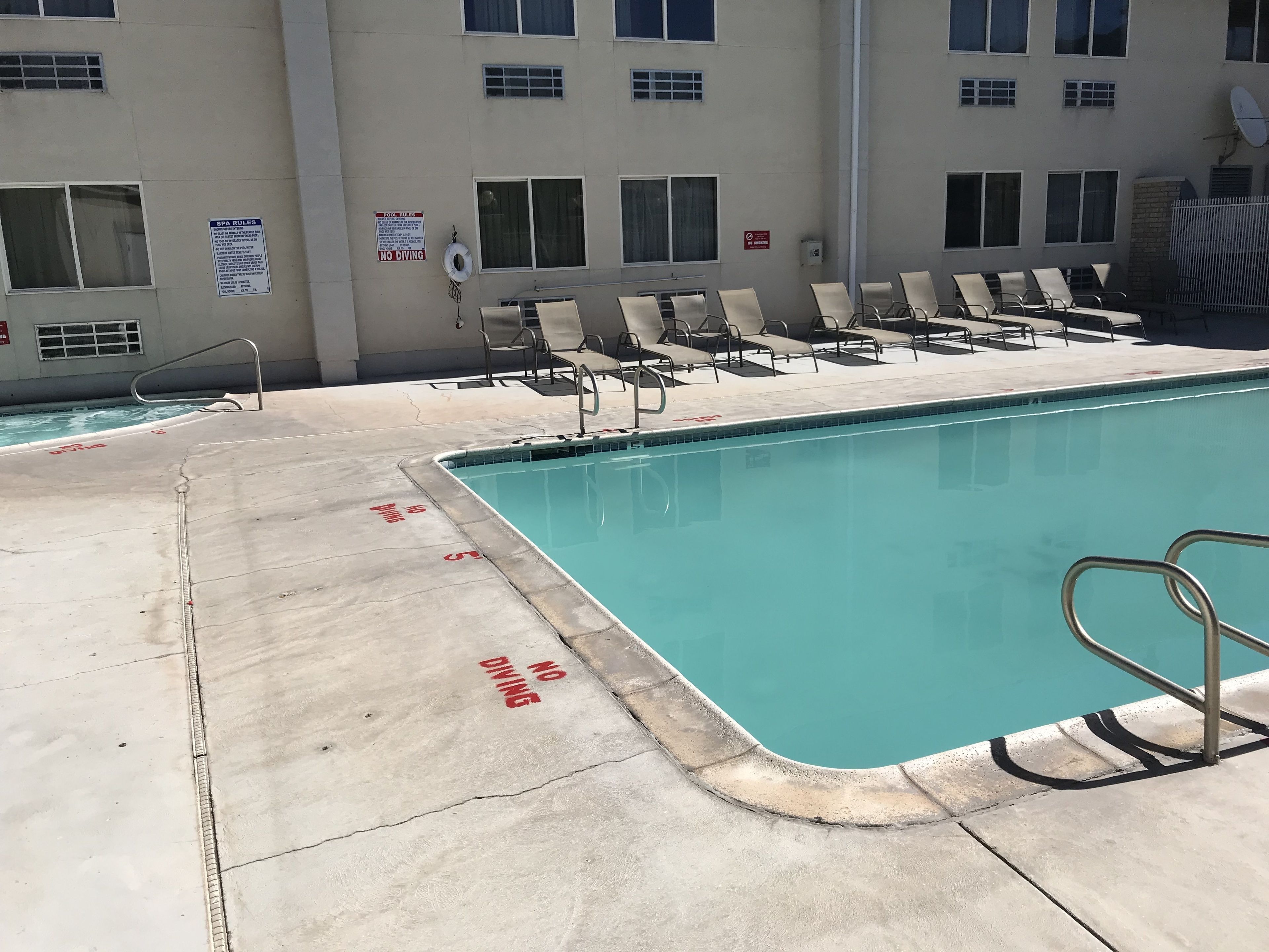 A swimming pool with lounge chairs and a no diving sign.